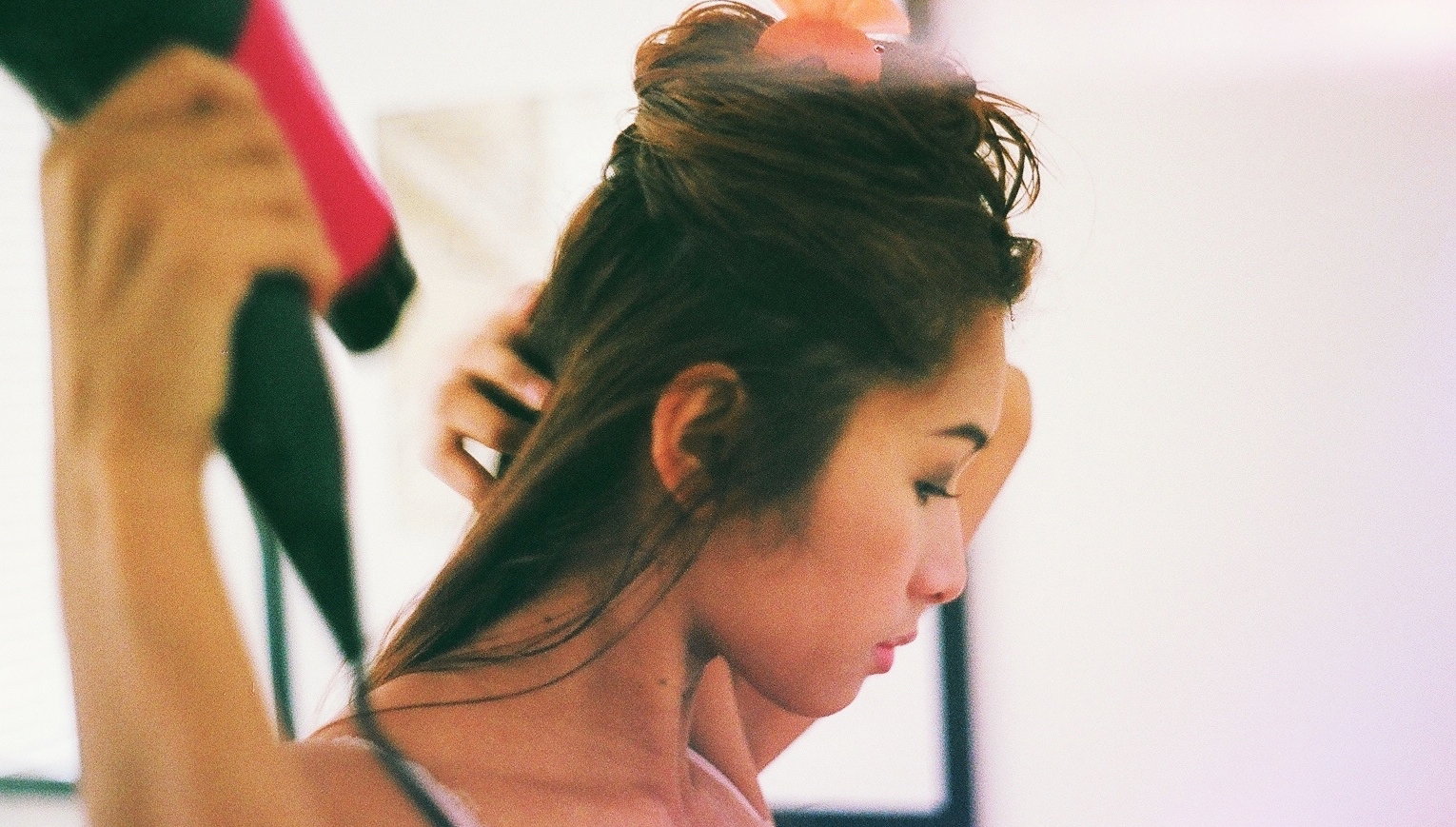 Young Woman Blow Drying Hair At Home