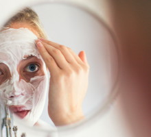 a Young woman with blue eyes applying a beauty mask.