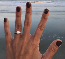 Cropped Hand Of Woman Showing Wedding Ring At Beach Against Sky During Sunset