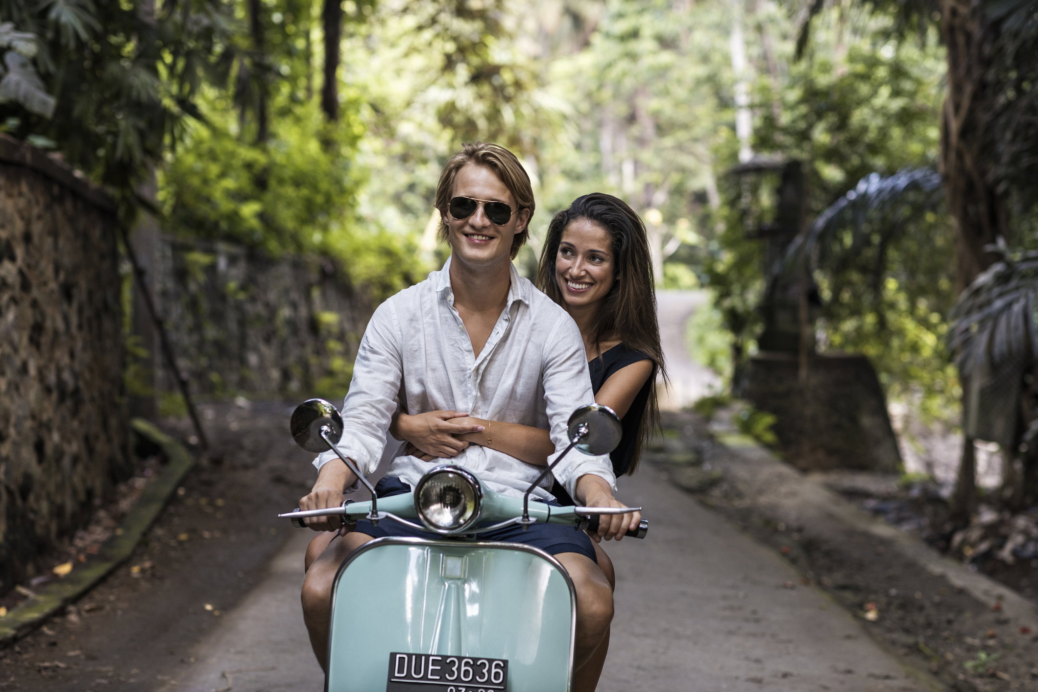 Young couple riding classic scooter during vacation in Bali