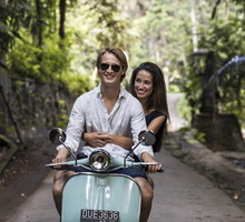 Young couple riding classic scooter during vacation in Bali