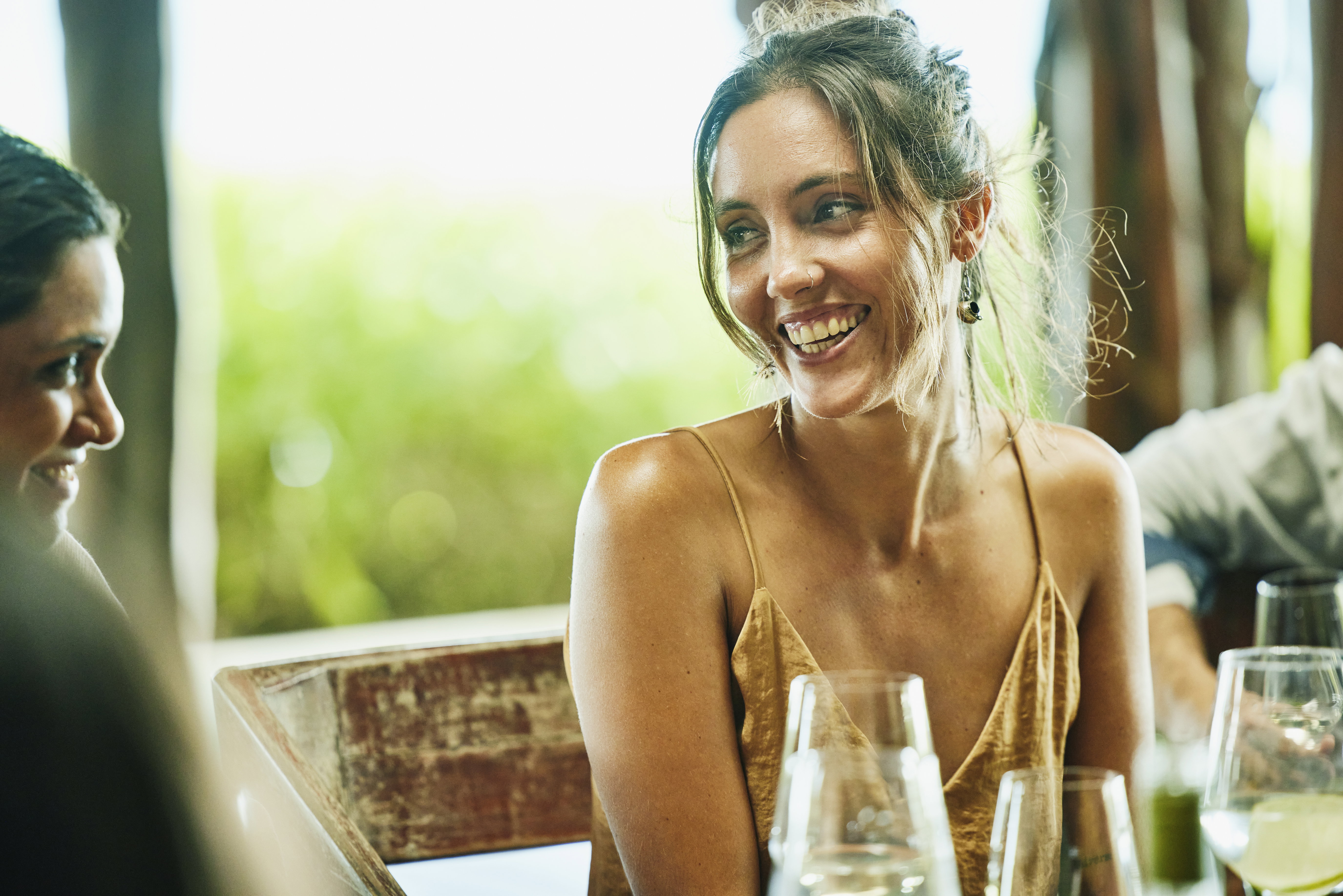 Medium wide shot of smiling woman dining with friends during wedding reception dinner at luxury tropical villa