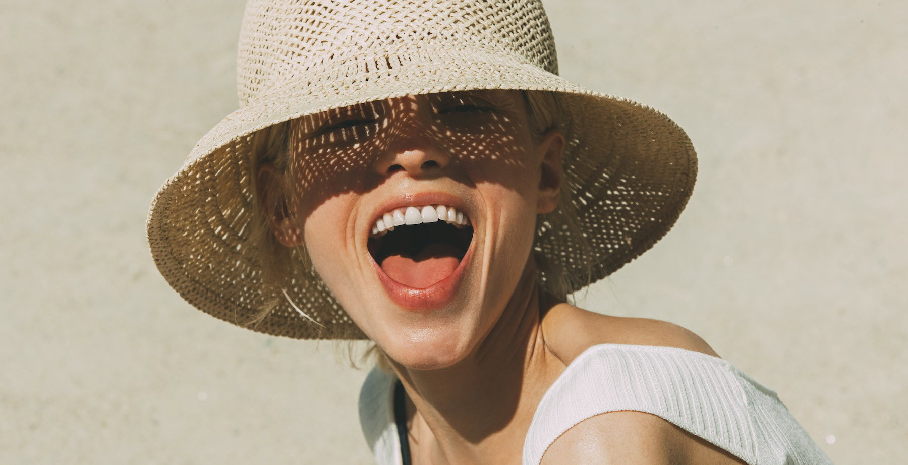 Portrait of laughing blond woman wearing summer hat