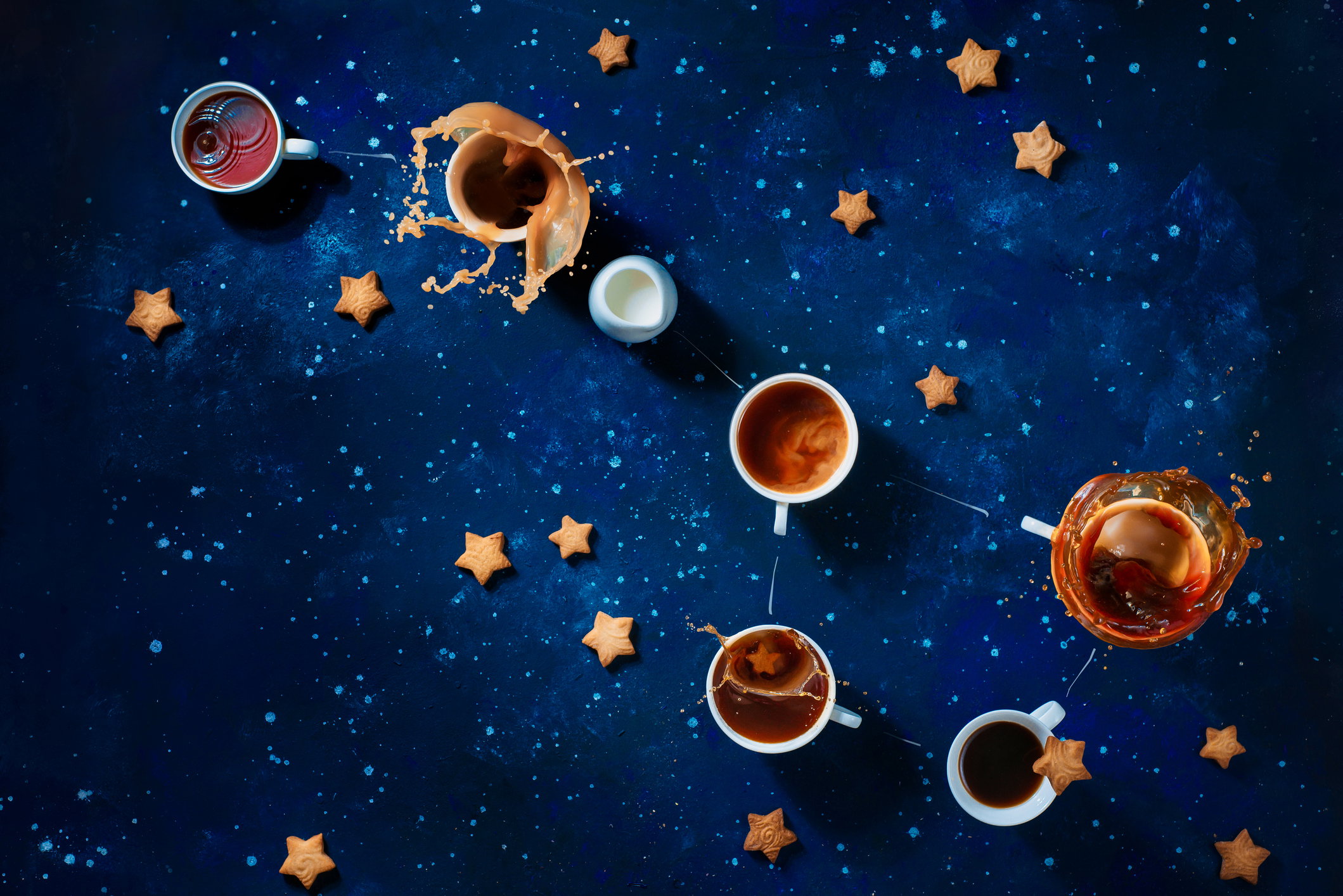 Big Dipper from coffee cups with splashes and star-shaped cookies, creative astronomy flat lay. High-speed food photography with copy space.