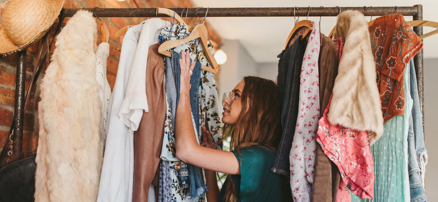 Side View Of Young Woman Hanging Clothes On Rack At Home