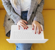 Businesswoman sitting on yellow couch, using laptop
