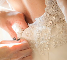 Bridesmaid Helping Bride With Dressing In Domestic Room