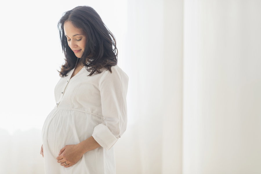 Pregnant Hispanic woman touching her belly