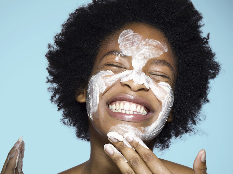 Young female applying face cream / mask