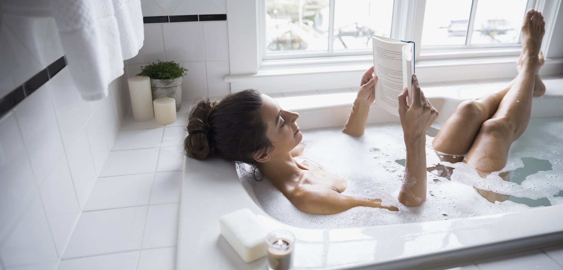 Woman reading book in bubble bath