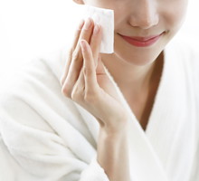 Woman cleaning face with cotton pad