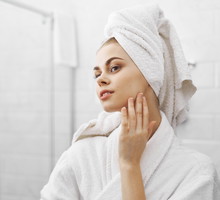 A beautiful woman looks in the mirror in the bathroom, care for the skin