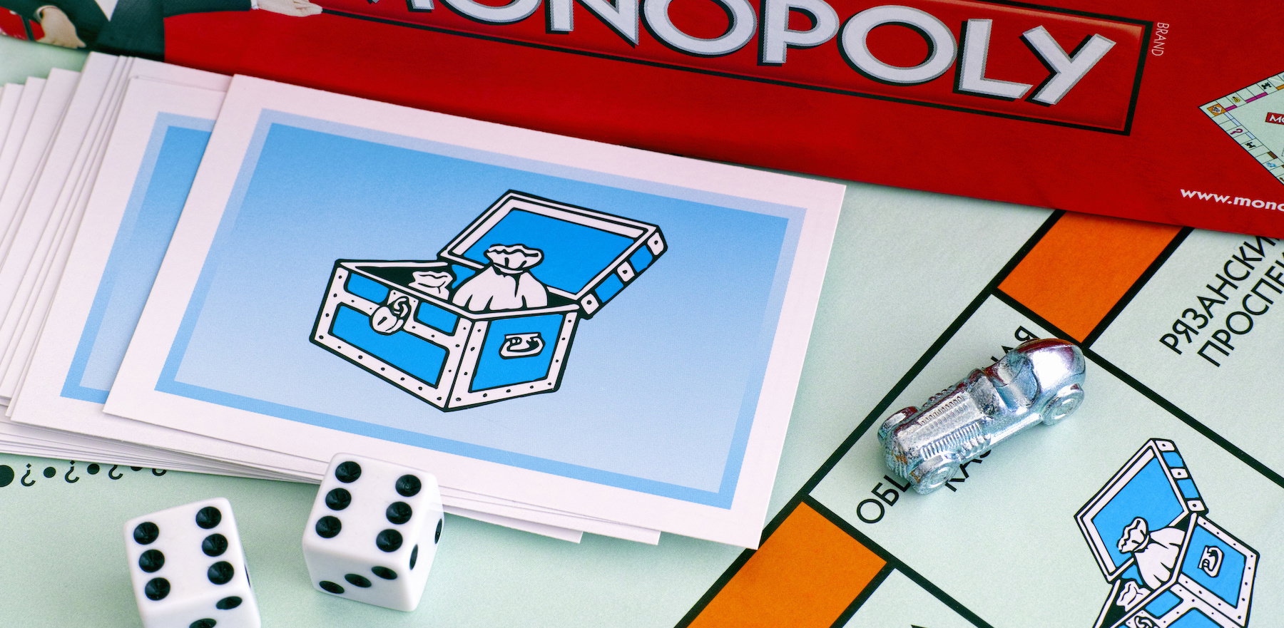 Monopoly Board Game box, Community Chest Cards, tokens, dices on gameboard.