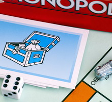 Monopoly Board Game box, Community Chest Cards, tokens, dices on gameboard.