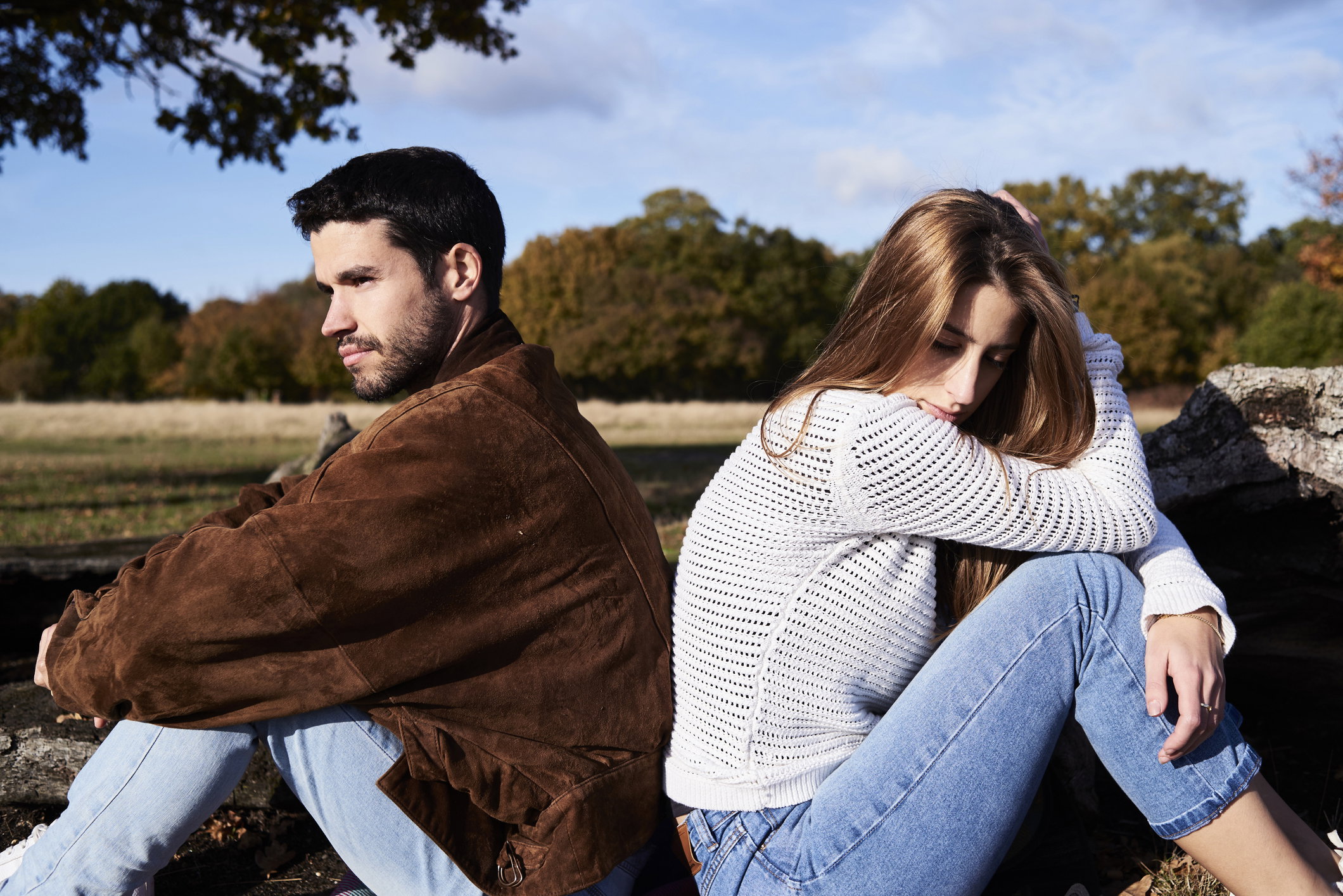 Serious couple sitting back to back in a park