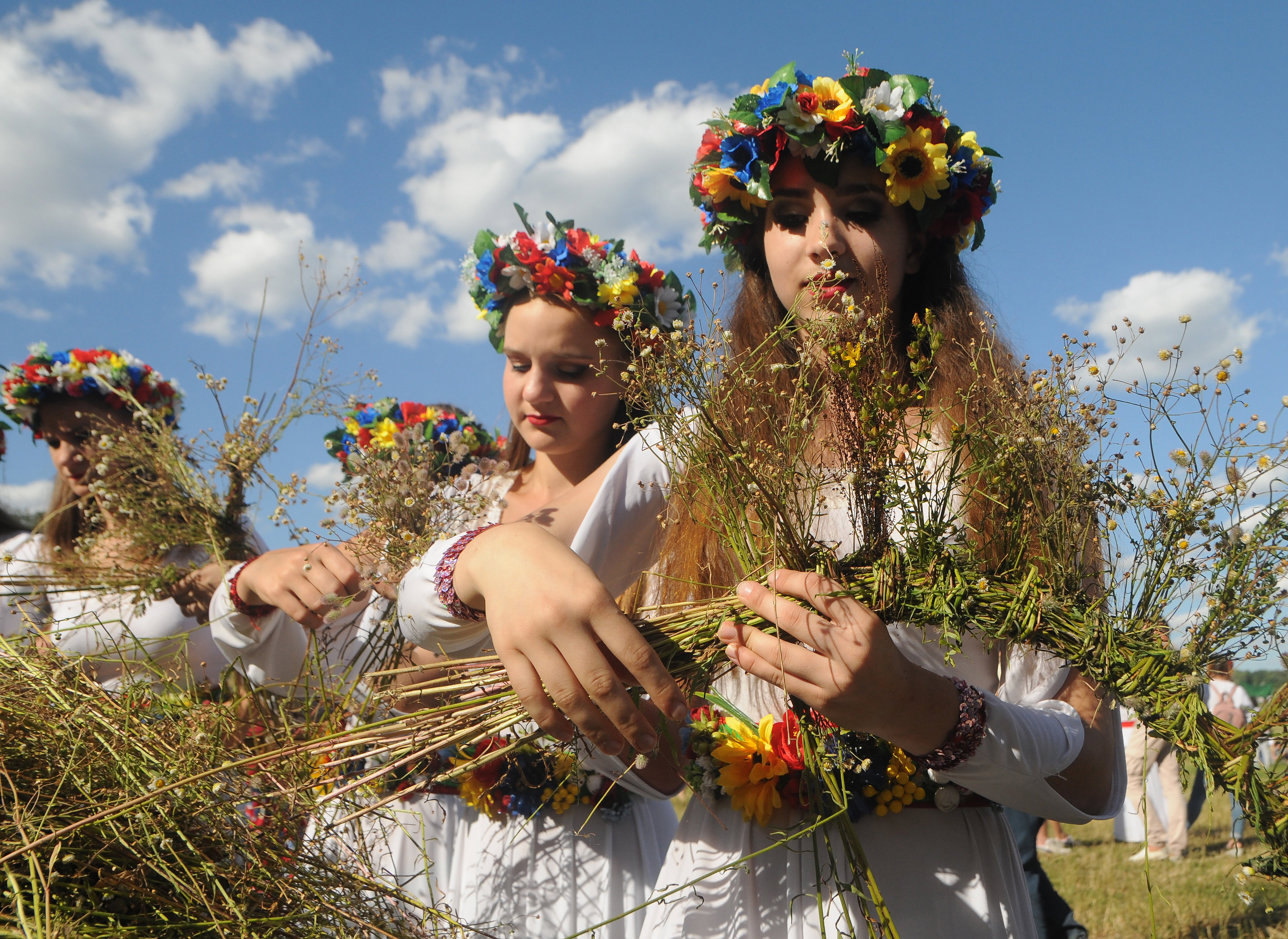 Women weave wreaths of wild flowers during a celebration in