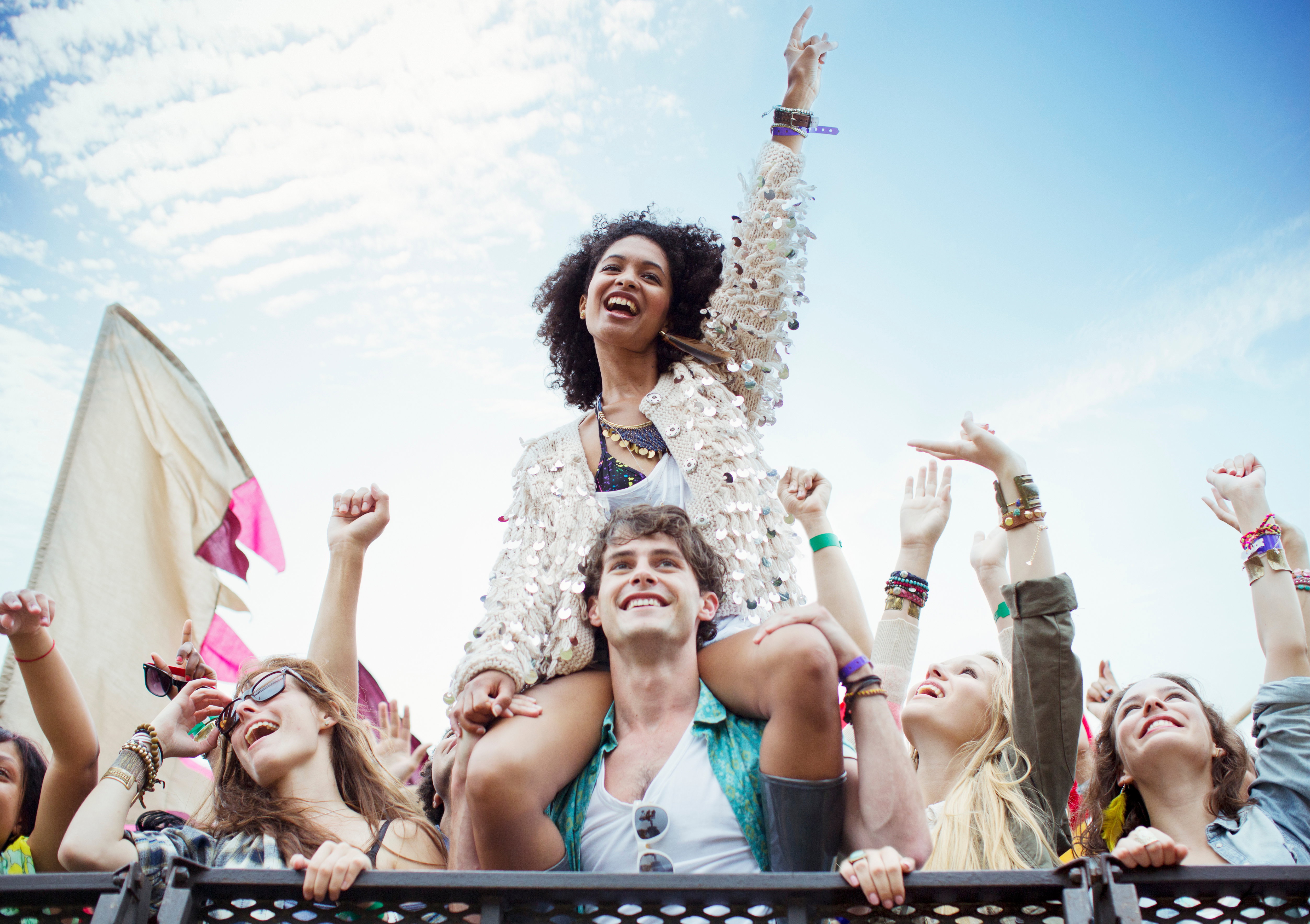 Cheering woman on man shoulders at music festival