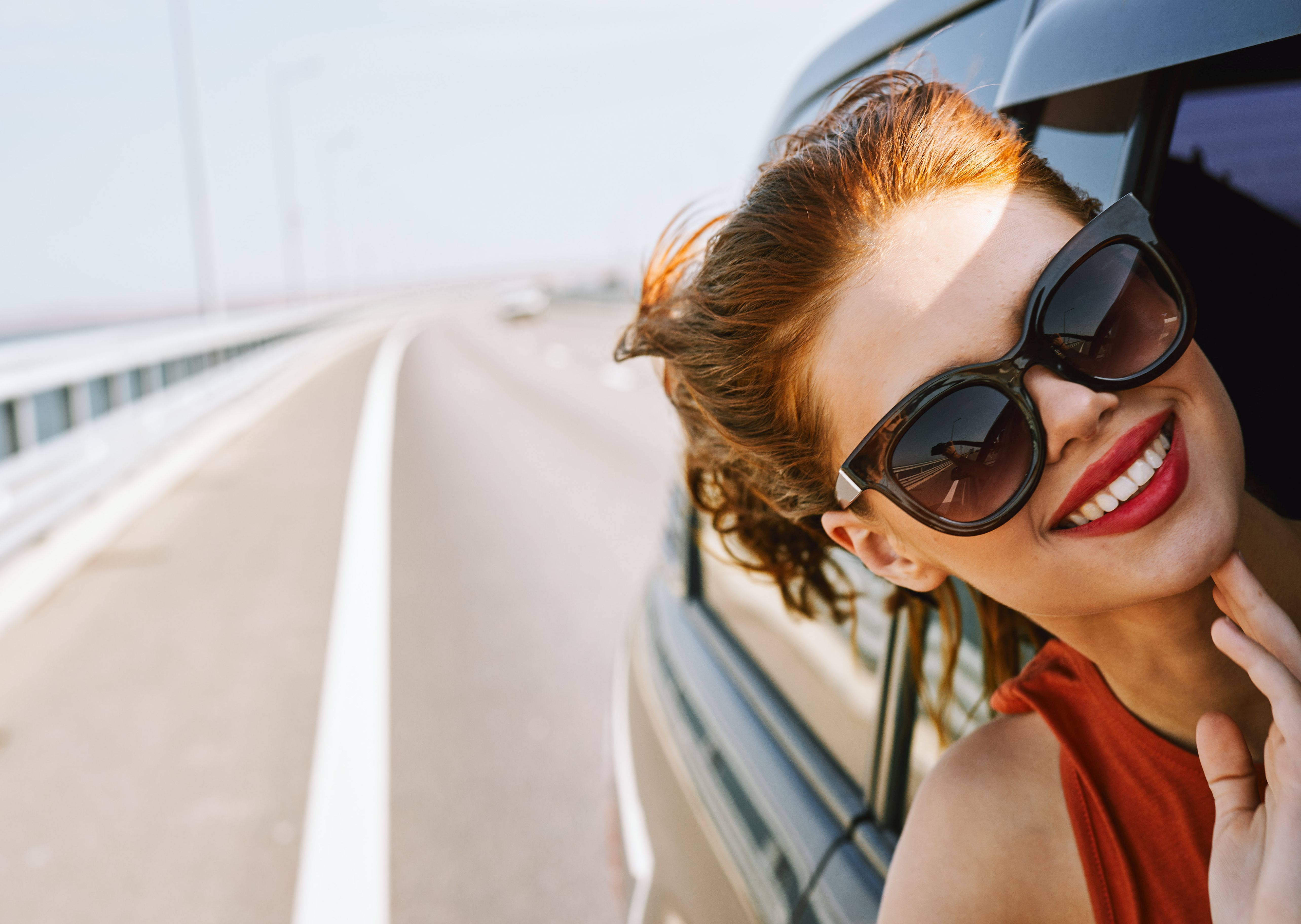 woman looking out of car window wearing sunglasses travel lifestyle