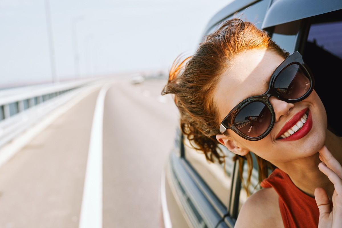 woman looking out of car window wearing sunglasses travel lifestyle