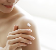 woman applying body lotion on shoulder