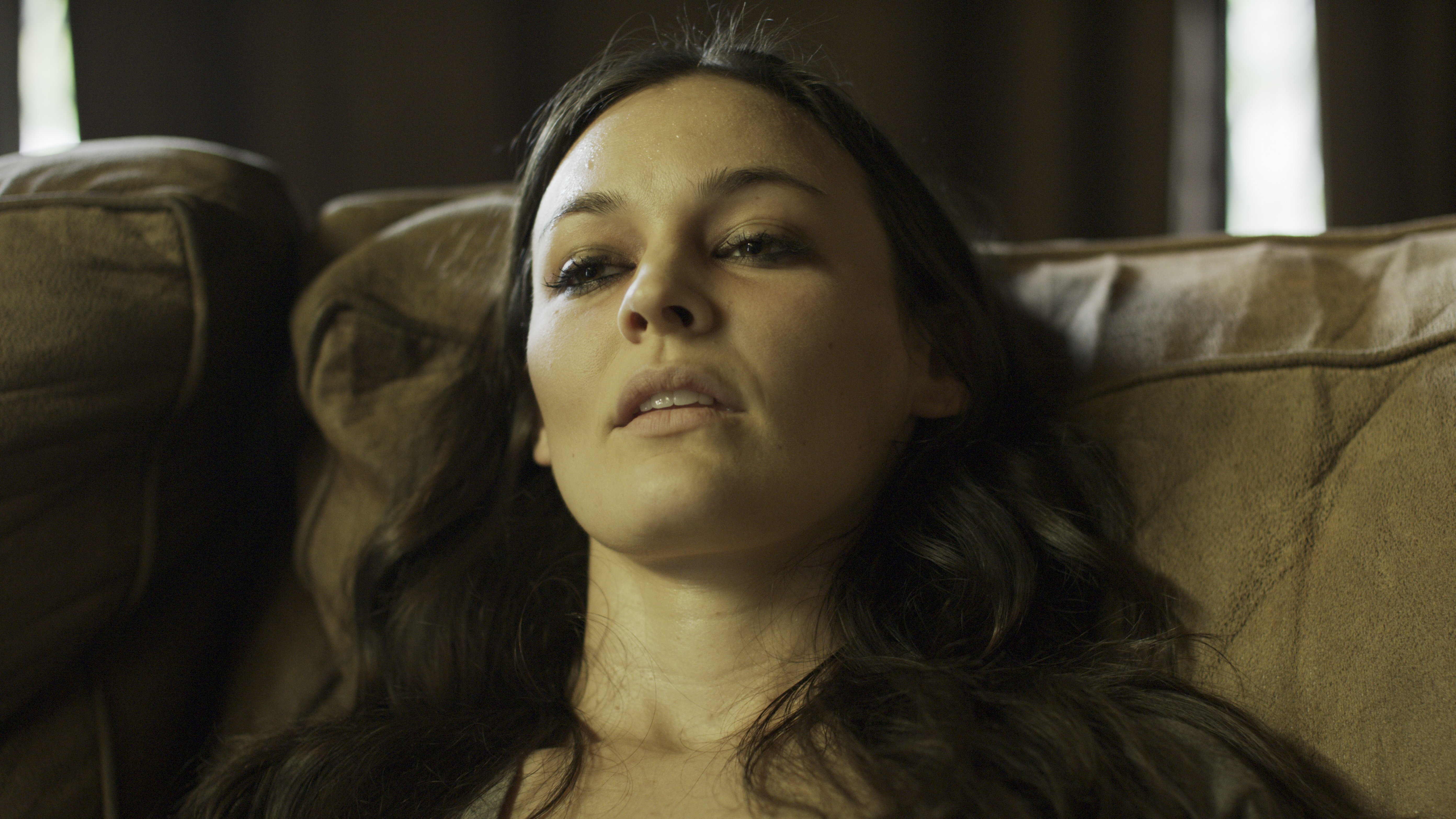 Close up of dazed woman with brown hair sitting on sofa