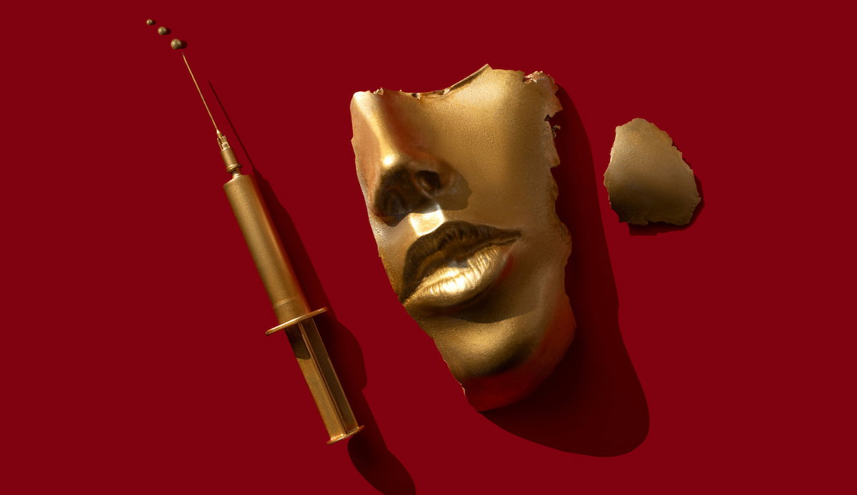 Gold colored syringe and face/ mask on the red background.