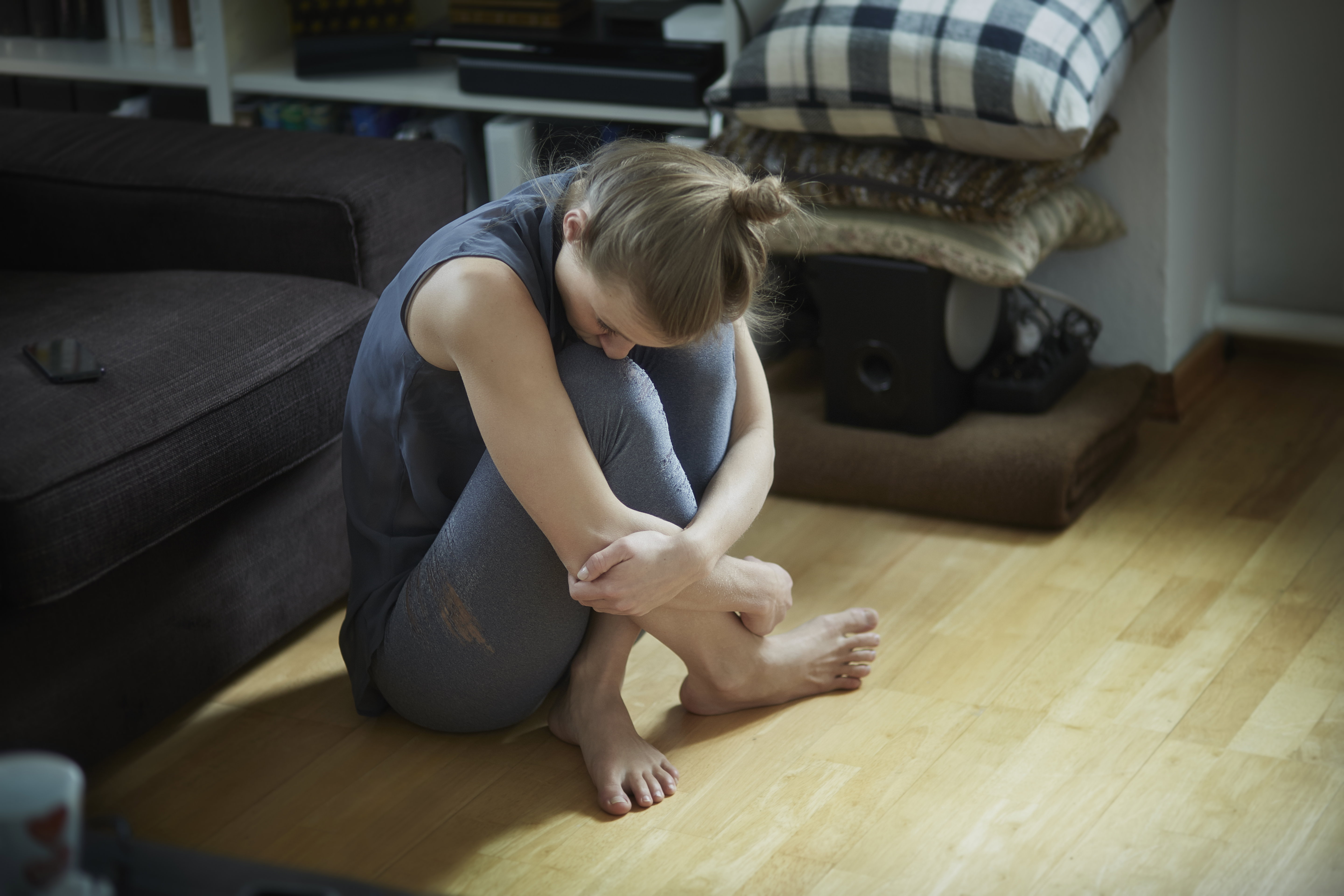 Sad young woman sitting on floor