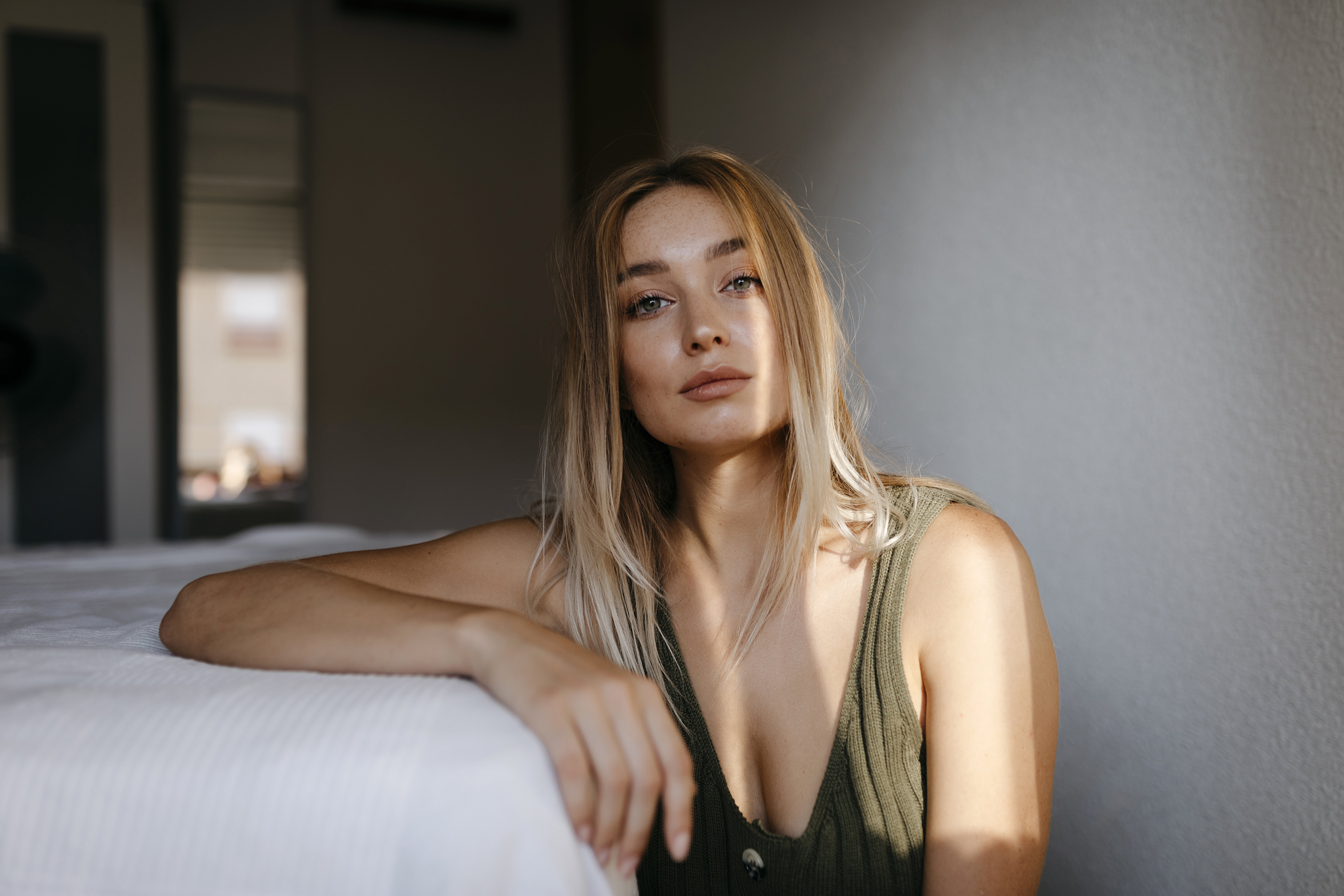 Seductive young woman sitting by bed in bedroom at home