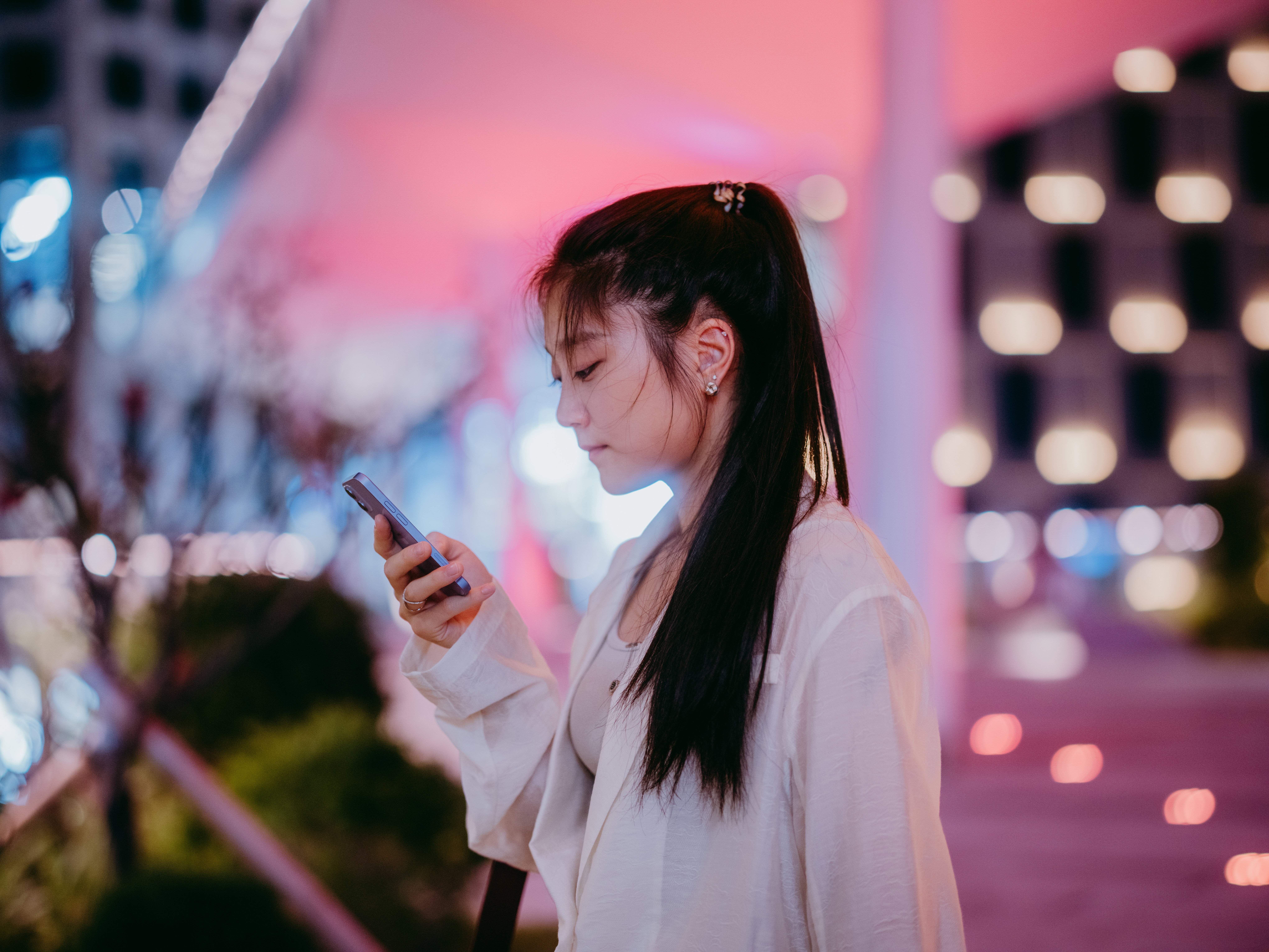 Businesswoman using smartphone while standing under office building after get off work