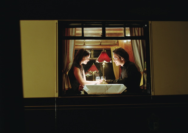 Young couple at table aboard train, exterior view, night