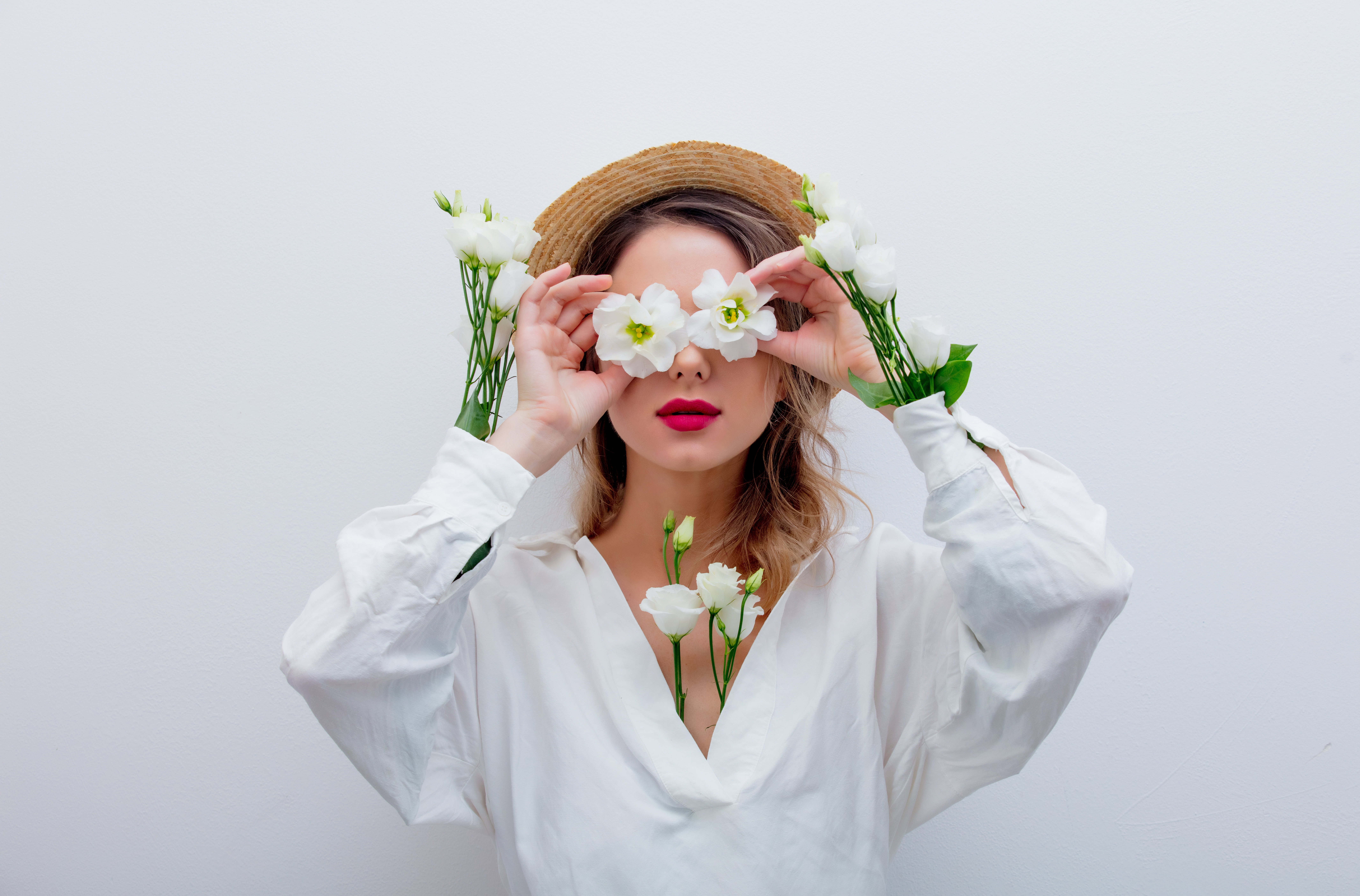 Beautiful woman with white roses in sleeves in hat on white backgroud. Springtime concept or Valentines Day holiday