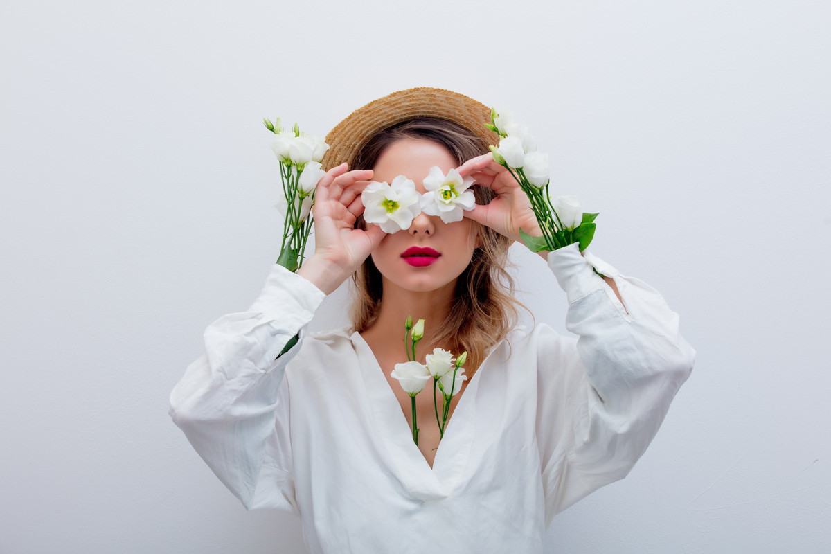 Beautiful woman with white roses in sleeves in hat on white backgroud. Springtime concept or Valentines Day holiday