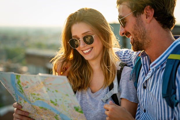 Happy couple on vacation sightseeing city with map. People travel fun love concept.