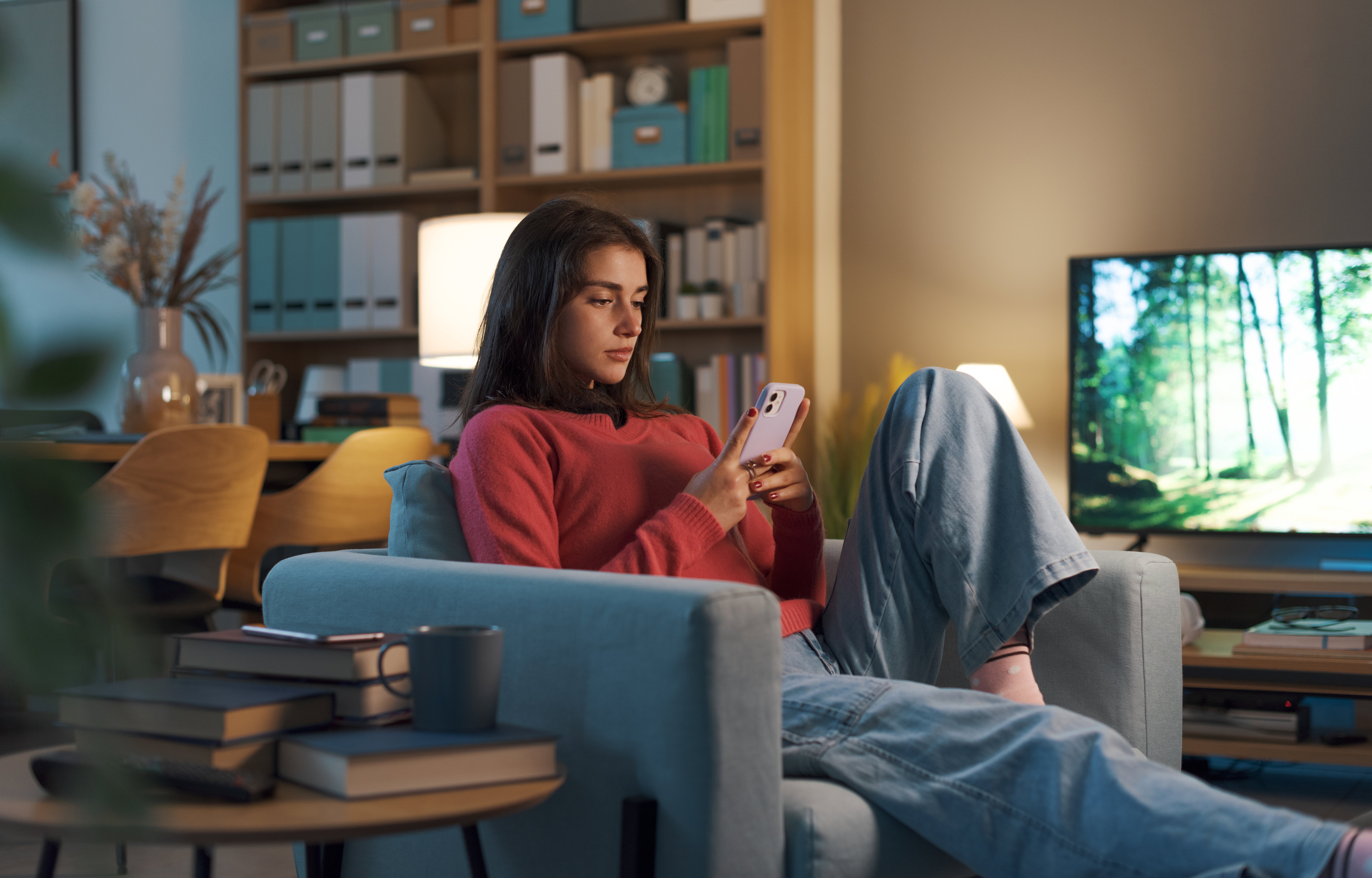 Girl relaxing on the armchair and using her smartphone
