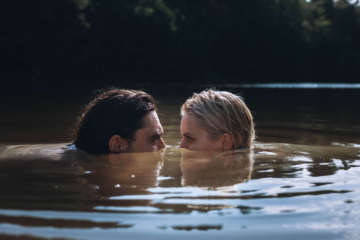 Confident man and delicate woman in problematic relationship swimming in lake, sank under water and looking at each other peeking out of surface with dissatisfied look.