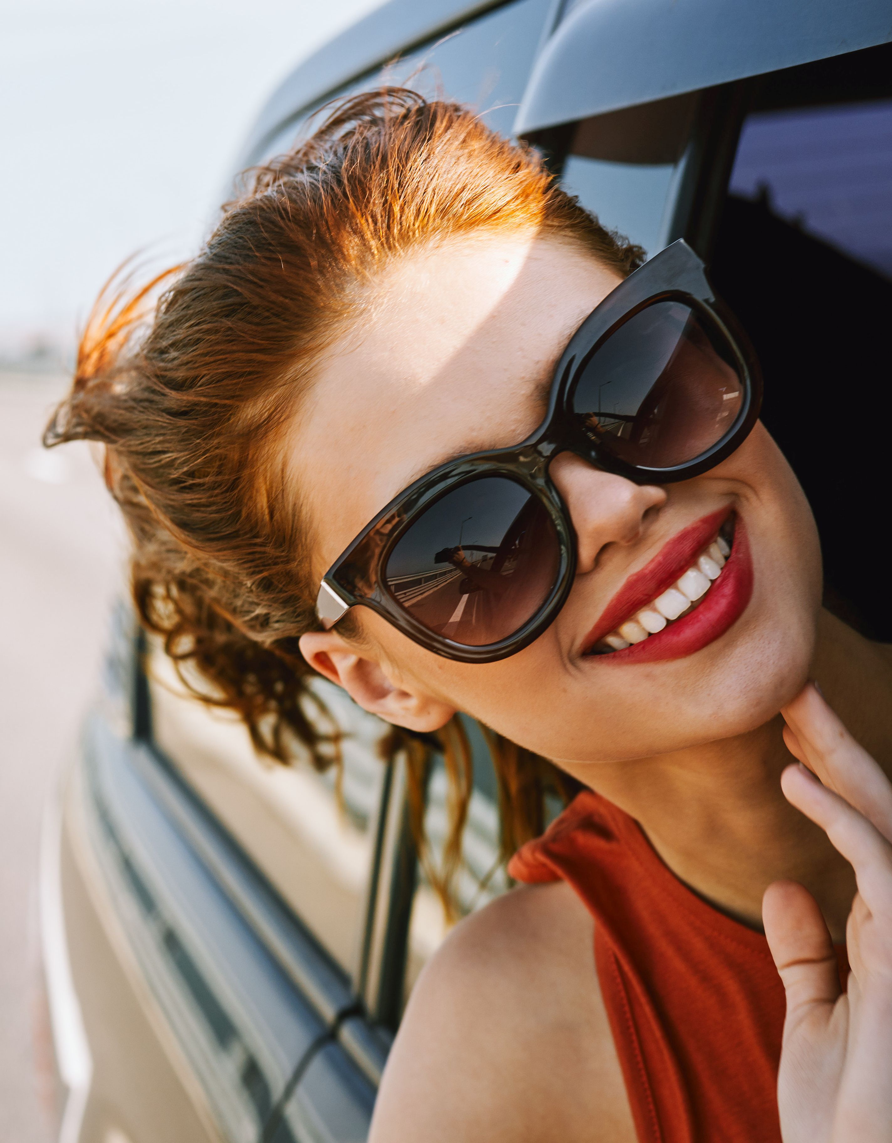 woman looking out of car window wearing sunglasses travel lifestyle