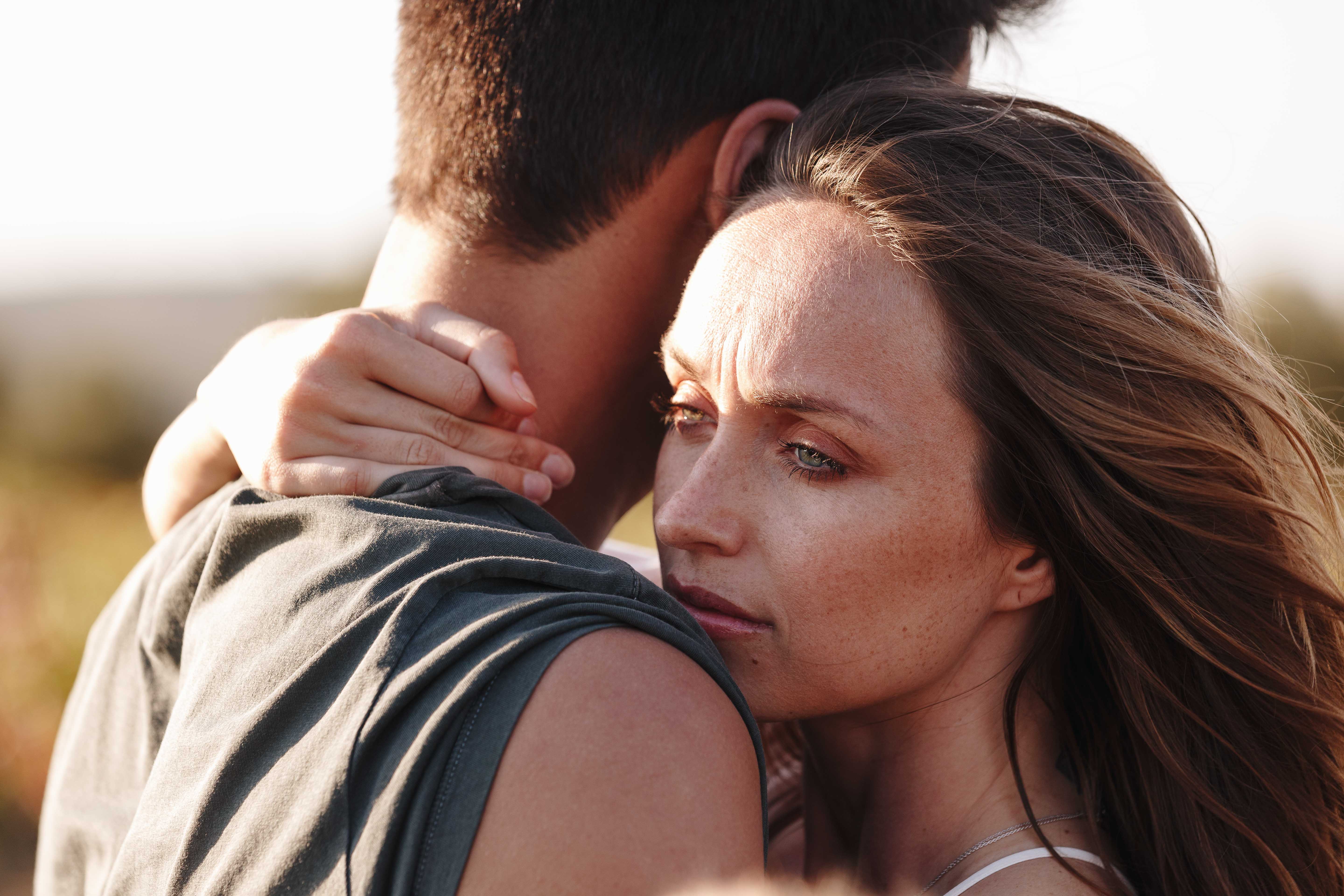 Couple hugging, woman looking worried