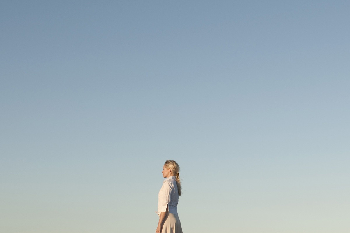 Couple standing back to back on pier, side view