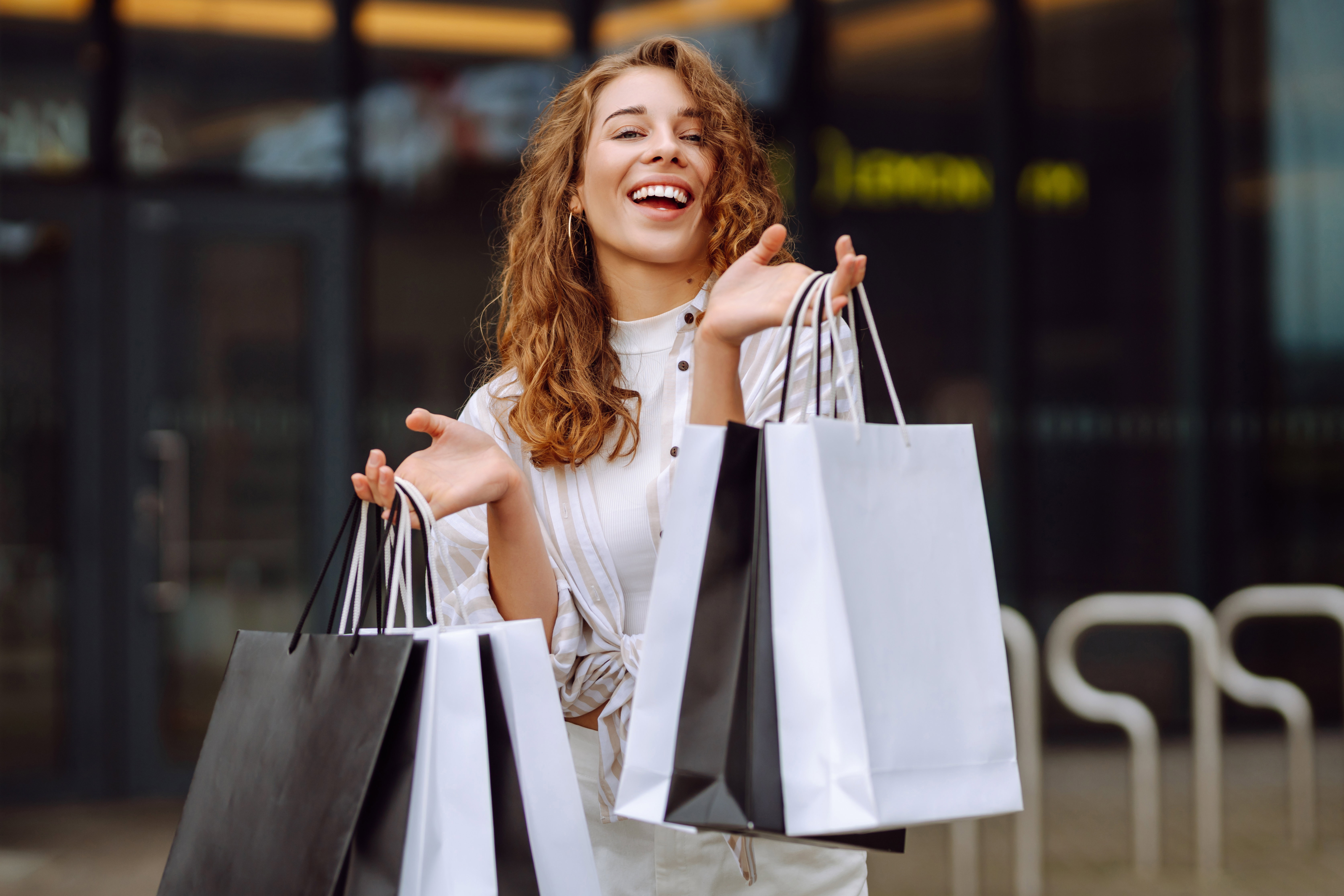 Stylish woman with shopping bags walks through the city streets. Consumerism, fashion, purchases, shopping, lifestyle concept.
