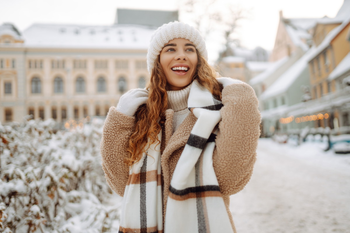 Happy woman having fun on a snowy street on a frosty morning in winter. A young woman walks through the city on a winter day. Concept of walks, weekends.