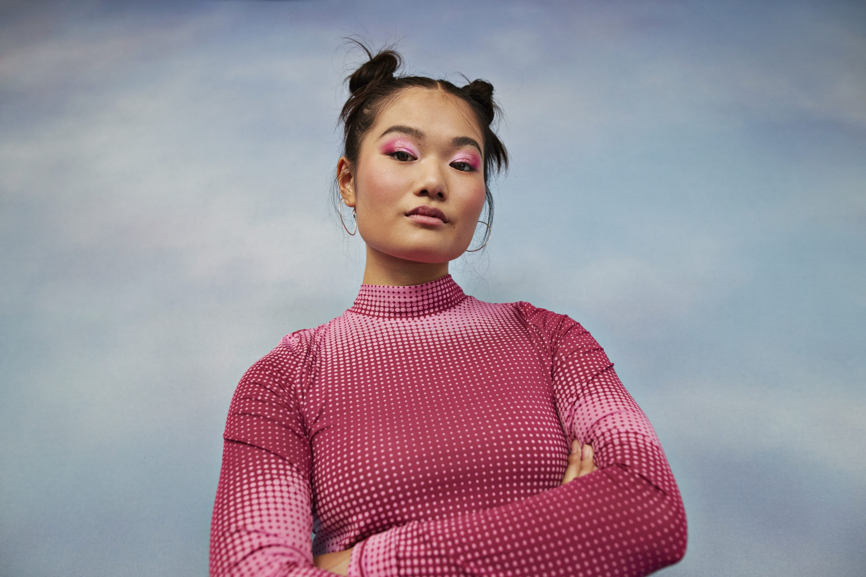 Portrait of confident teenage girl with arms crossed against colored background