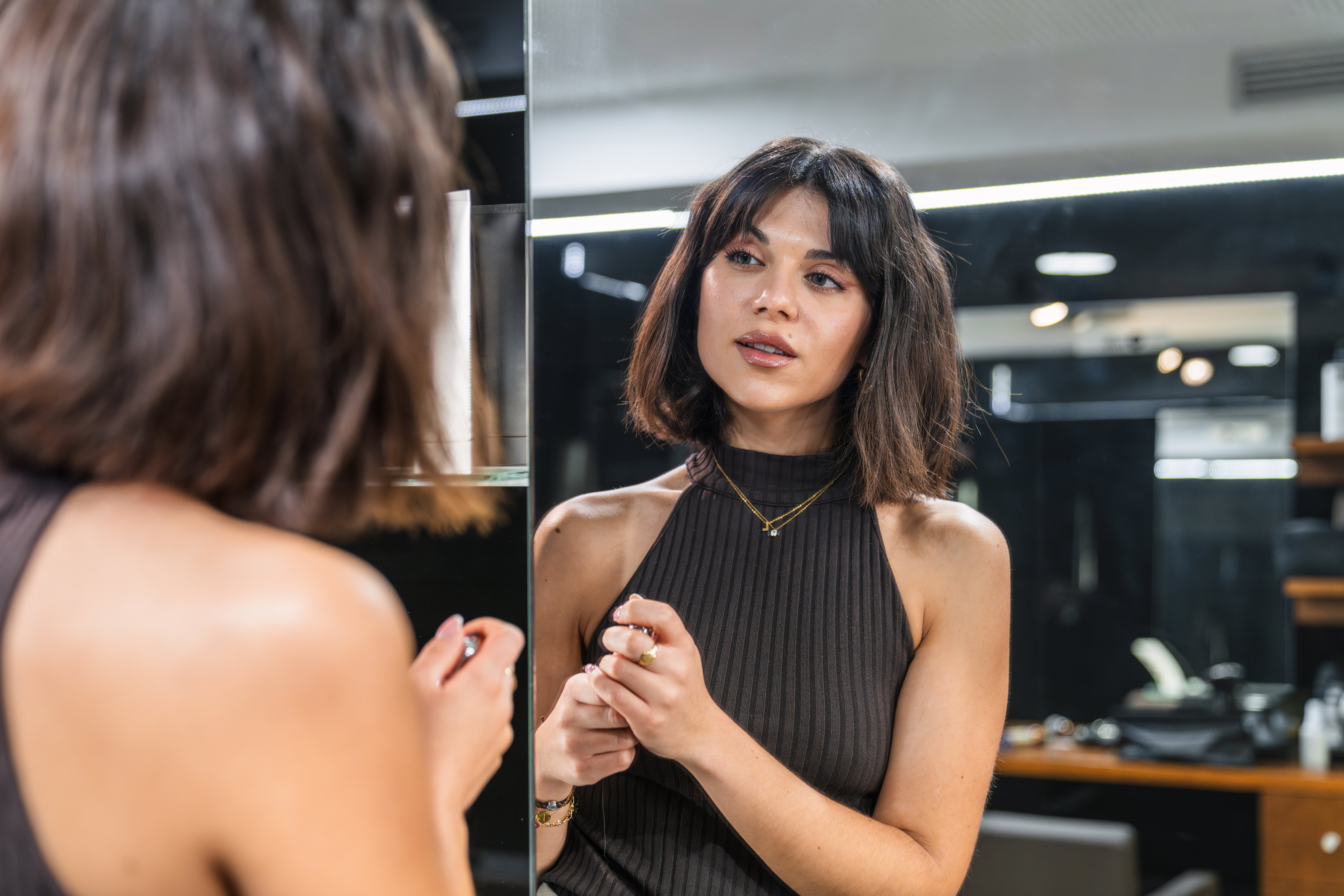 Young woman with short bob haircut admiring her new look in the salon mirror