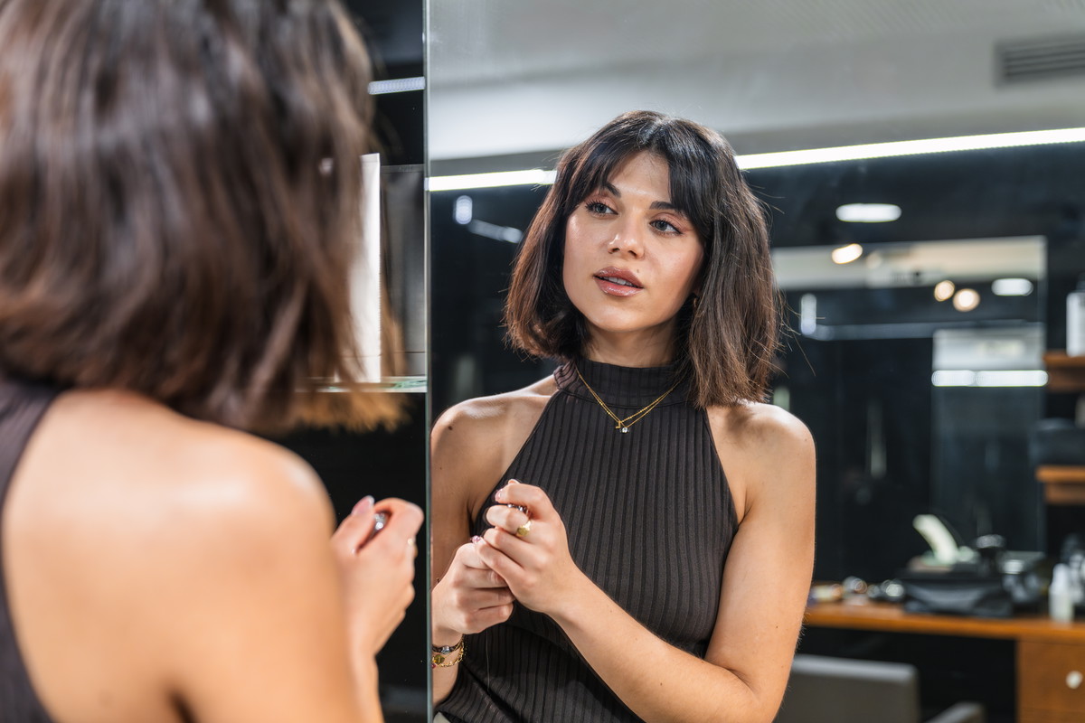 Young woman with short bob haircut admiring her new look in the salon mirror