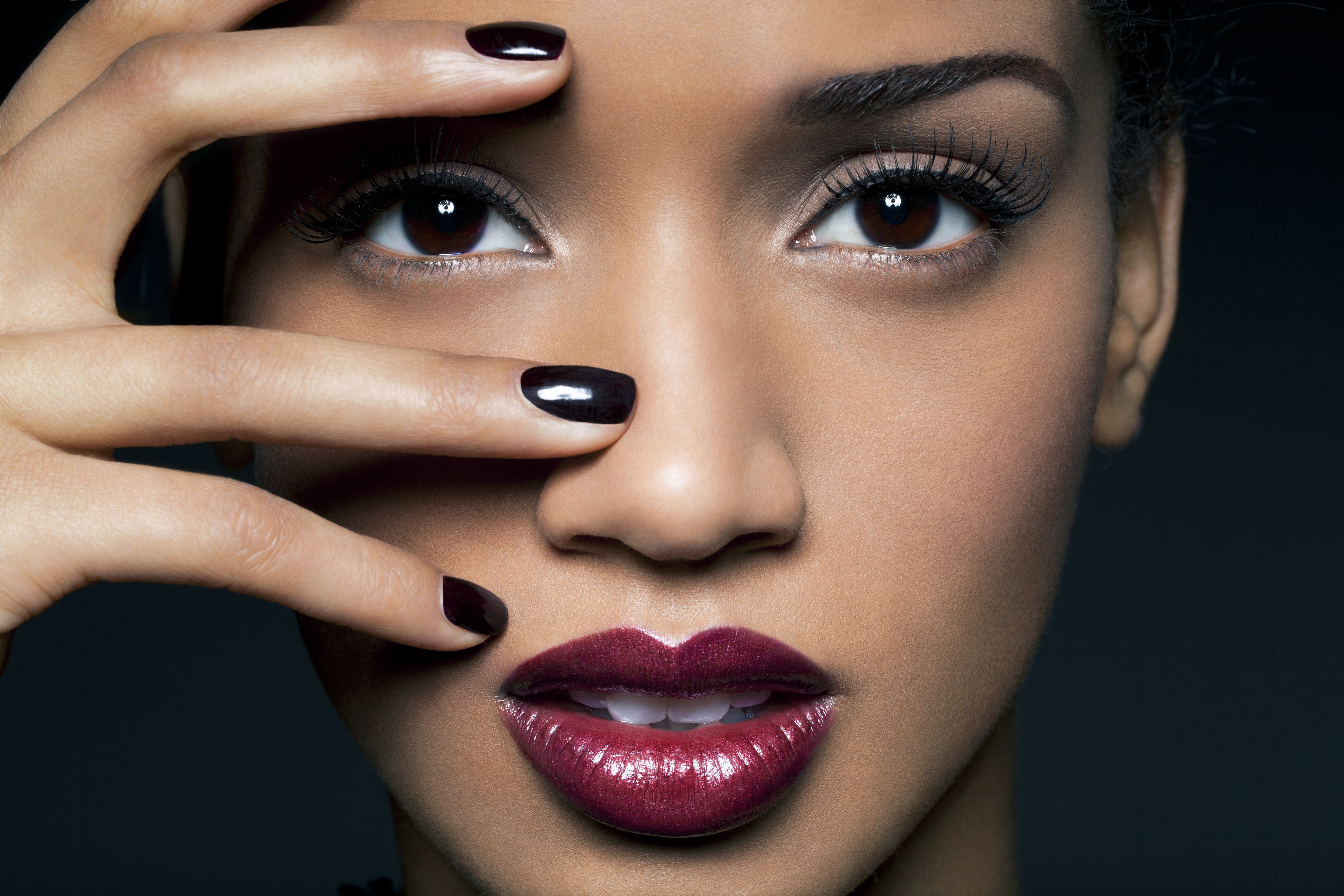 Young woman with red lips and black nail polish.