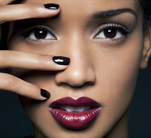Young woman with red lips and black nail polish.