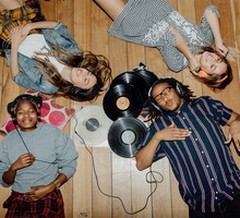 Group of young friends listening to music with vinyls scattered about