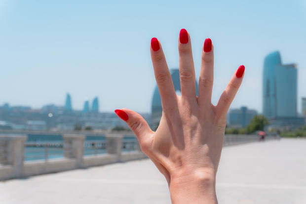 Hand with red nails raised against the skyline of Baku,Baku,Azerbaijan