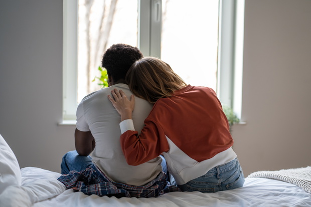 Woman putting head on man shoulder for support, comforting and consolation while looking at window