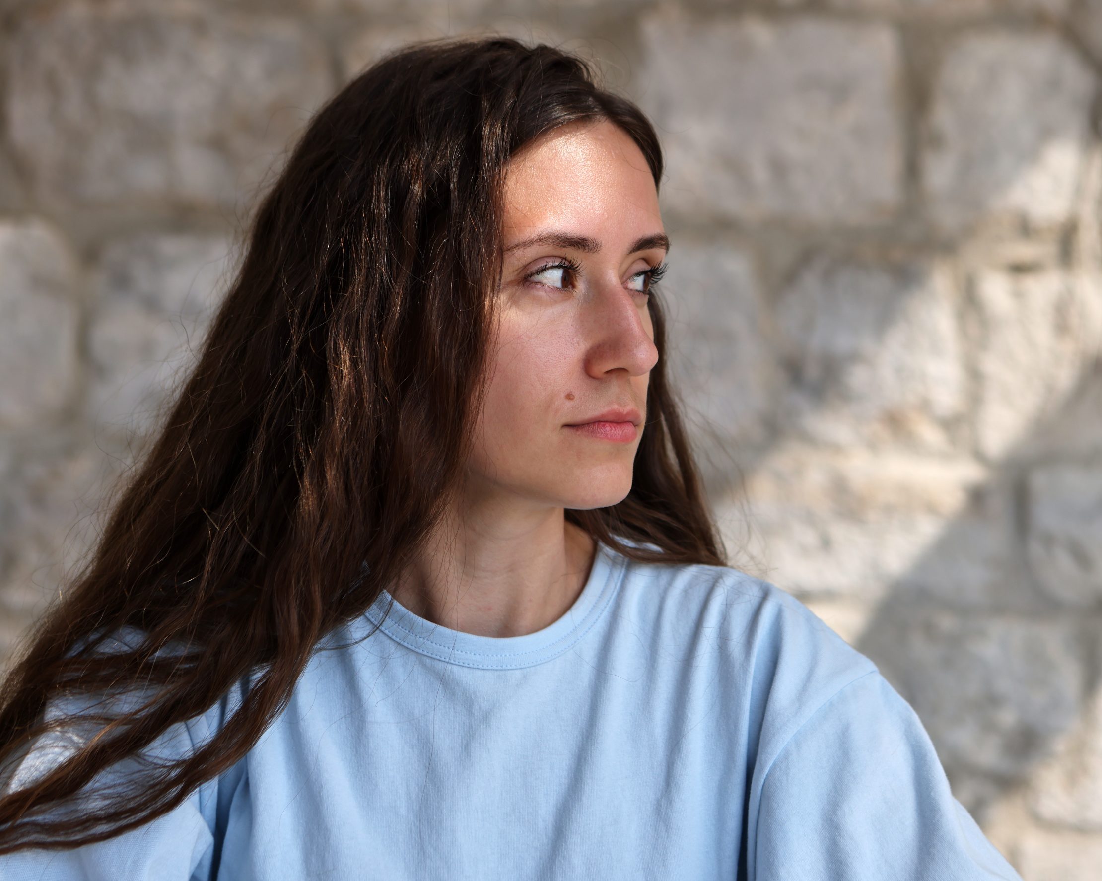 Uncertain woman looking away suspiciously against brick wall