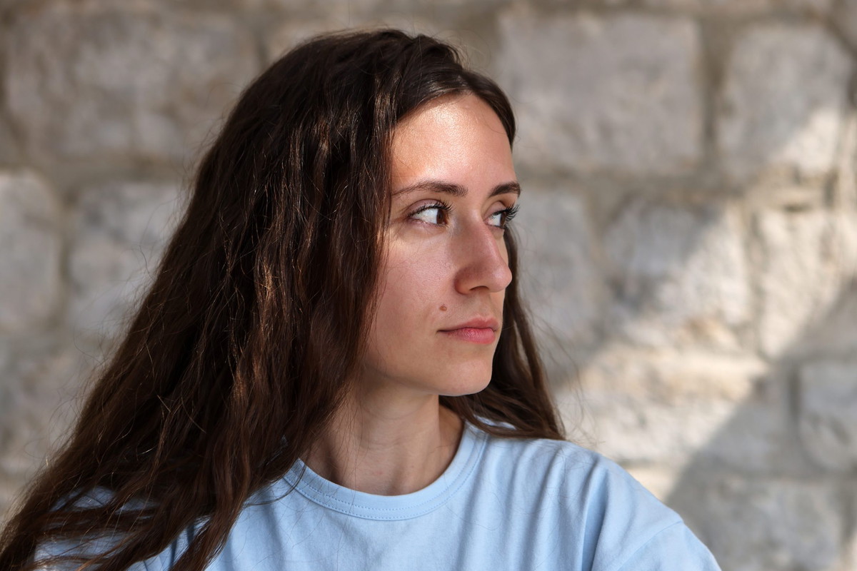 Uncertain woman looking away suspiciously against brick wall